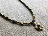 closeup of gold thunderbird pendant hung on metallic bead choker