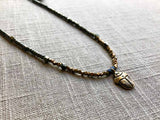 closeup of gold scarab pendant hung on metallic bead choker