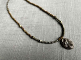 top view of antique snake pendant hung on metallic bead choker