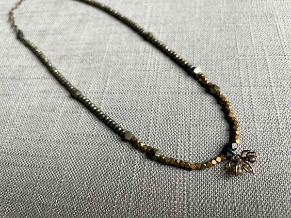 top view of antique insect pendant with pearls hung on metallic bead choker