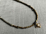 closeup of antique victorian pendant with pearl hung on metallic bead choker