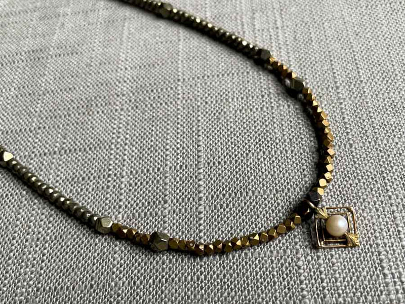 closeup of antique victorian pendant with pearl hung on metallic bead choker