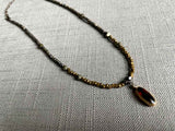 top view of antique citrine oval pendant hung on metallic bead choker