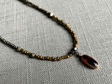 closeup of antique citrine oval pendant hung on metallic bead choker