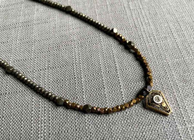 closeup of antique Art Deco pendant hung on metallic bead choker