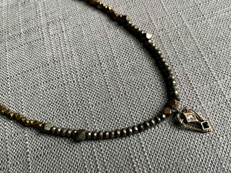 closeup of antique Art Deco pendant with diamond and sapphire hung on metallic bead choker