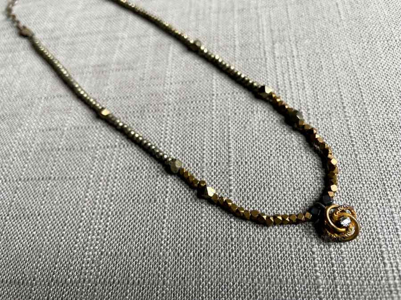 top view of antique love knot pendant with diamond hung on metallic bead choker