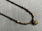 closeup of antique love knot pendant with diamond hung on metallic bead choker