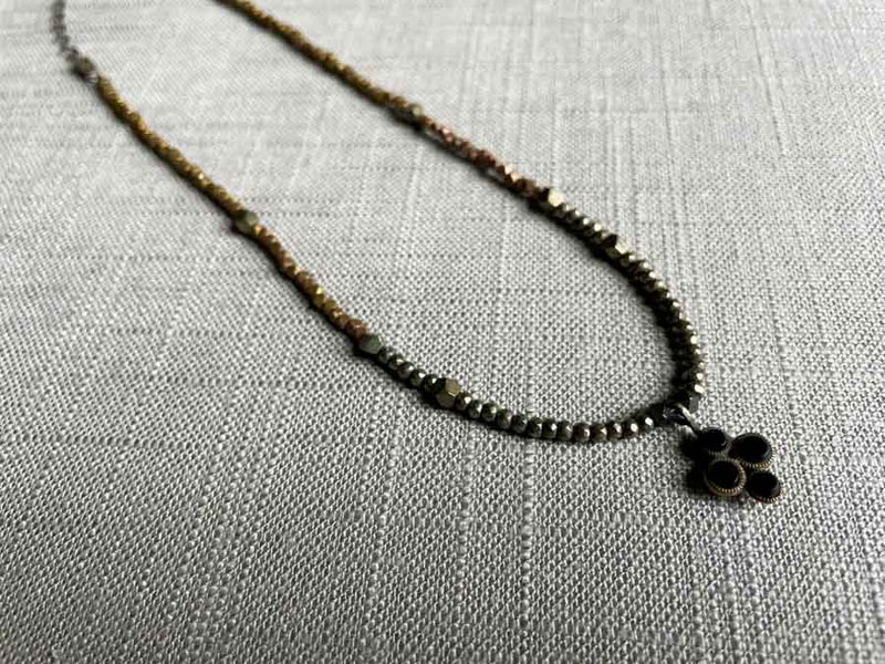 top view of antique black onyx dots pendant hung on metallic bead choker