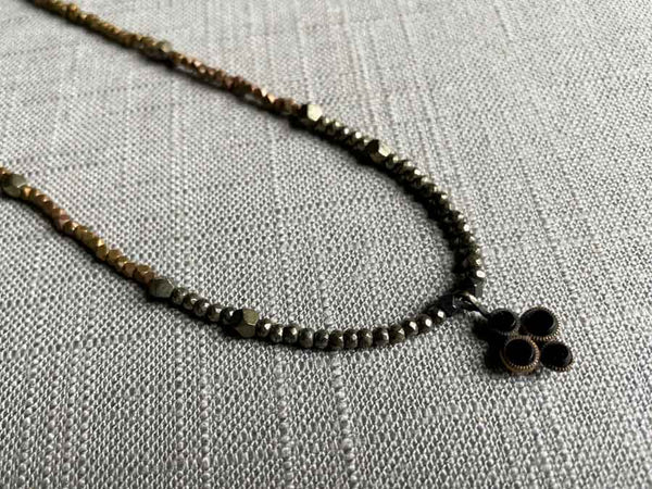 closeup of antique black onyx dots pendant hung on metallic bead choker