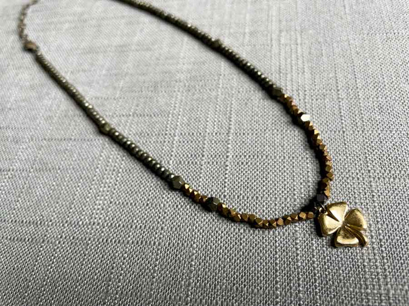 top view of antique four leaf clover pendant hung on metallic bead choker