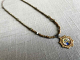 top view of antique madonna and child pendant hung on metallic bead choker