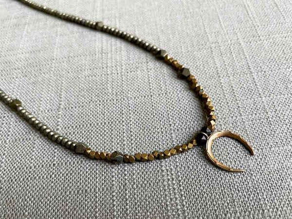 closeup of antique horseshoe pendant hung on metallic bead choker