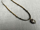 top view of antique bird pendant hung on a metallic bead choker