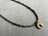 closeup of antique horseshoe pendant hung on a metallic bead choker