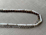 side view of gemstone bead necklace comprising white pearl, neutral shadow quartz and exotic wood