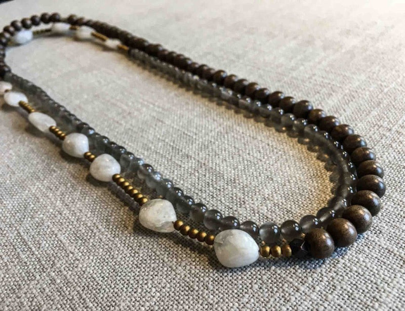 top view of gemstone bead necklace comprising white moonstone, grey moonstone, exotic wood and matte gold