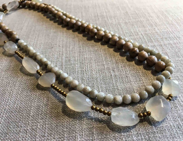 top view of gemstone bead necklace comprising white chalcedony, off-white siberian moonstone, exotic wood and matte gold