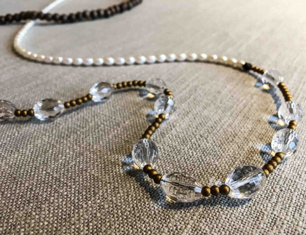 closeup of gemstone bead necklace comprising white pearl, clear faceted natural quartz, exotic wood and gold hematite