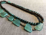 top view of gemstone bead necklace comprising aqua chalcedony, green chrysoprase, exotic wood and matte gold