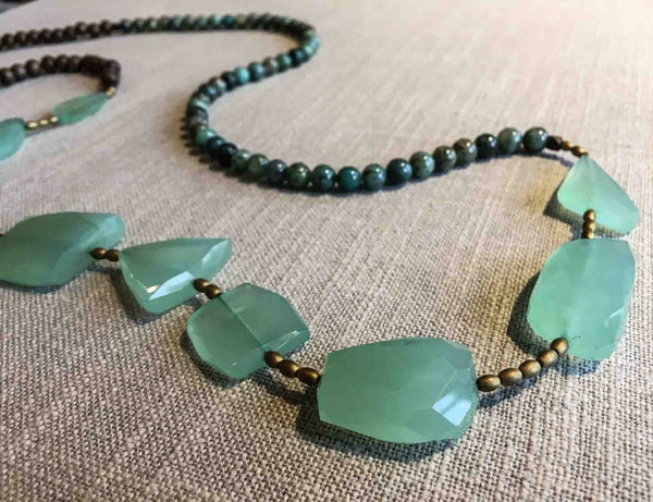 closeup of gemstone bead necklace comprising aqua chalcedony, green chrysoprase, exotic wood and gold hematite