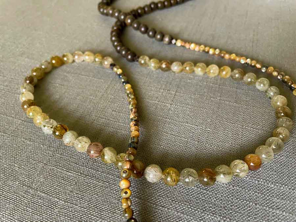 closeup of gemstone bead necklace comprising green tourmaline, exotic wood and neutral shell