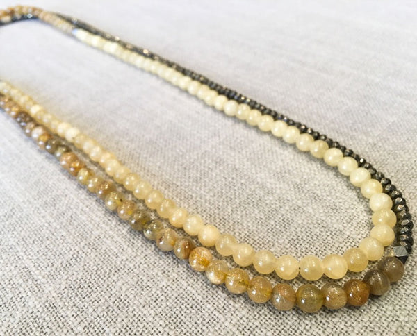 top view of gemstone bead necklace comprising yellow jade, pyrite and beige rutilated quartz