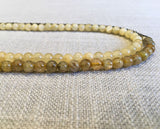 side view of gemstone bead necklace comprising yellow jade, metallics and beige rutilated quartz