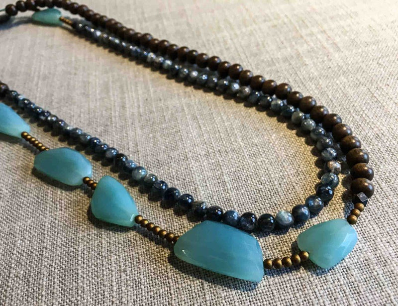 top view of gemstone bead necklace comprising blue chalcedony, blue kyanite, exotic wood and gold hematite