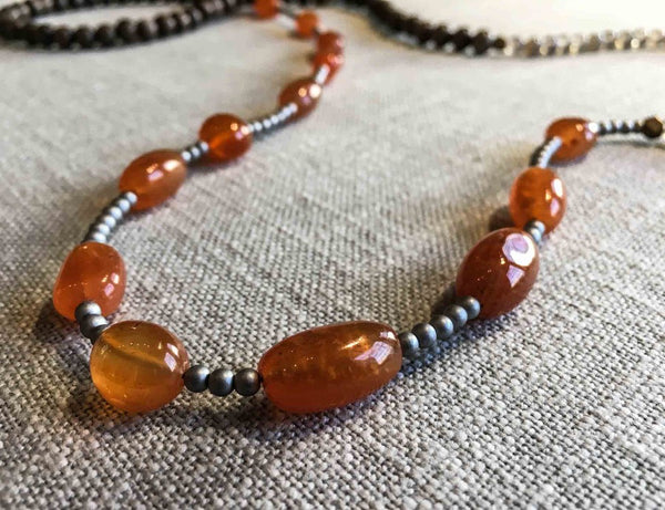 closeup of gemstone bead necklace comprising orange carnelian, grey moonstone, exotic wood and silver hematite