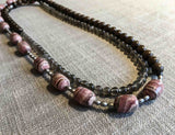 top view of gemstone bead necklace comprising pink rhodochrosite, grey moonstone, exotic wood and matte silver