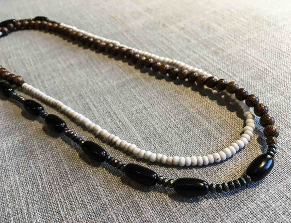 top view of gemstone bead necklace comprising white conch shell, black horn, exotic wood and dark grey pyrite