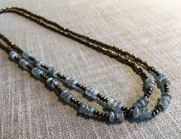 top view of gemstone bead necklace comprising light blue aquamarine, bronze and dark grey pyrite