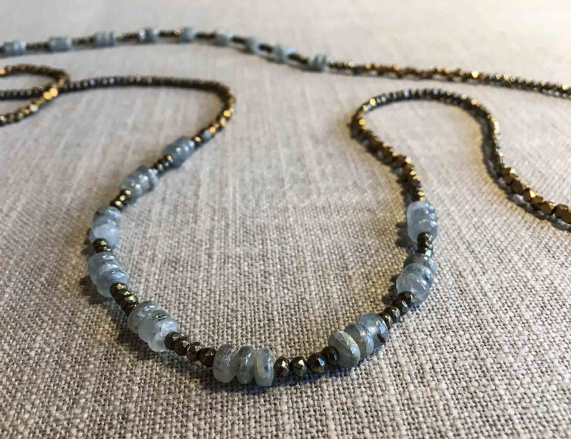 closeup of gemstone bead necklace comprising light blue aquamarine, bronze and pyrite