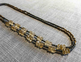 top view of gemstone bead necklace comprising faceted yellow citrine, bronze and dark grey pyrite