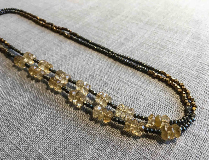 top view of gemstone bead necklace comprising faceted yellow citrine, bronze and dark grey pyrite