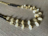 side view of gemstone bead necklace comprising white moonstone, dark bronze and golden pyrite