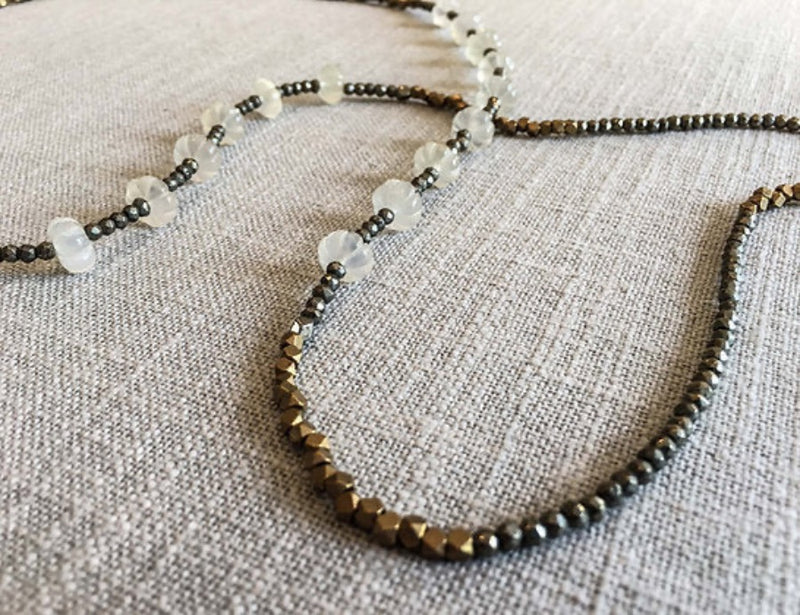 closeup of gemstone bead necklace comprising white moonstone, bronze, dark grey pyrite