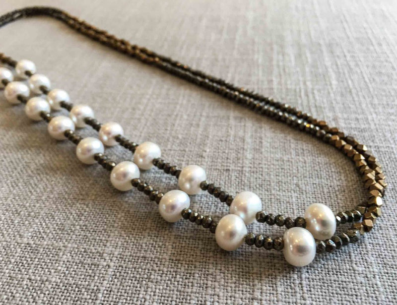 top view of gemstone bead necklace comprising white pearl, bronze and dark grey pyrite