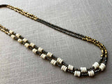 top view of gemstone bead necklace comprising beige bone, bronze and dark grey pyrite