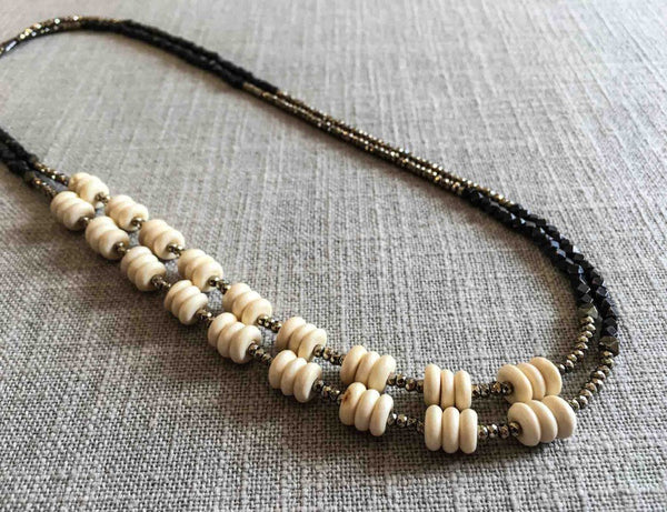 top view of gemstone bead necklace comprising beige bone, dark bronze and golden pyrite