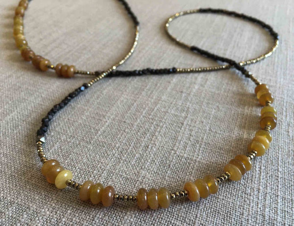 closeup of gemstone bead necklace comprising yellow jade, dark bronze and metallics