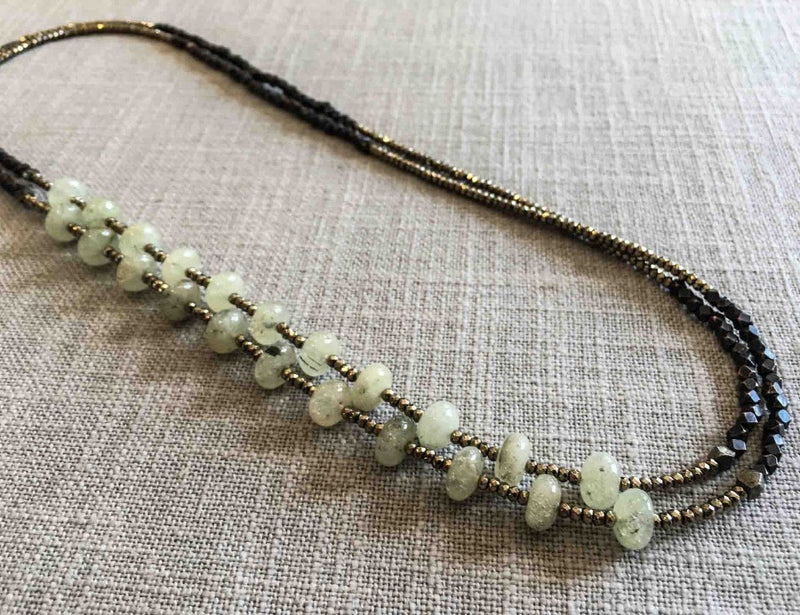 top view of gemstone bead necklace comprising light green prehnite, dark bronze and golden pyrite