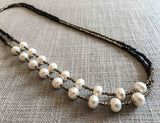 top view of gemstone bead necklace comprising white pearl, dark bronze and golden pyrite