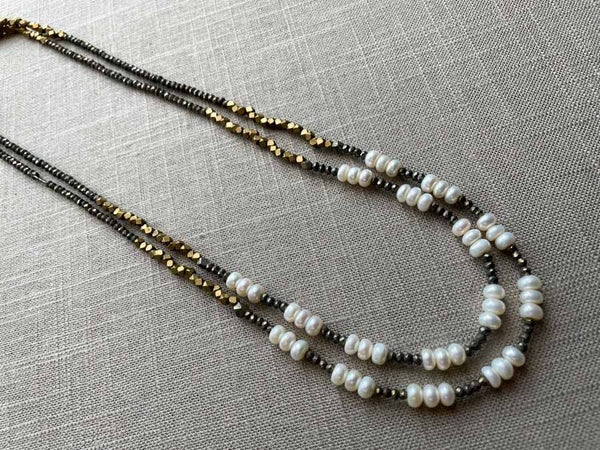 top view of gemstone bead necklace comprising white pearl, bronze and dark grey pyrite