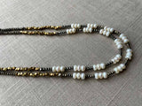 side view of gemstone bead necklace comprising white pearl, bronze and dark grey pyrite