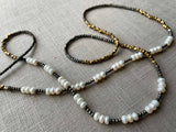 closeup of gemstone bead necklace comprising white pearl, bronze and dark grey pyrite