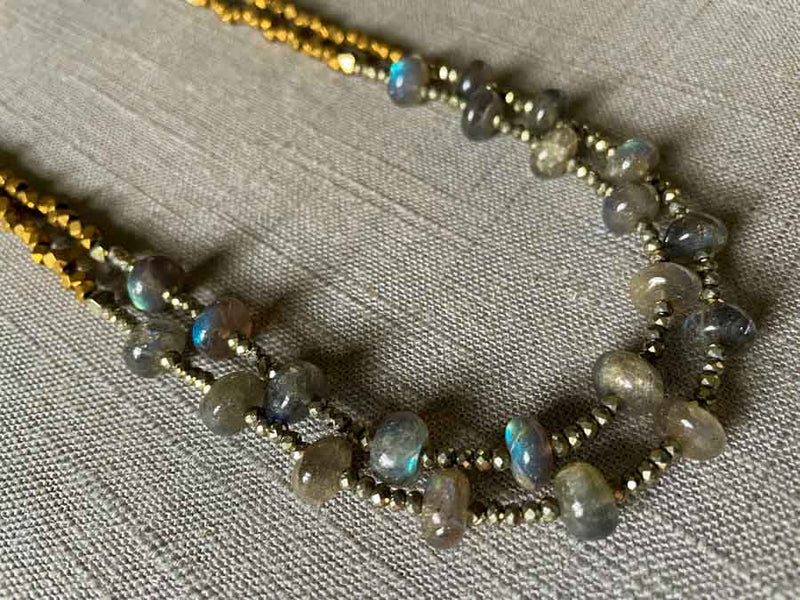 Closeup of gemstone bead necklace comprising blue labradorite, bronze and dark grey pyrite