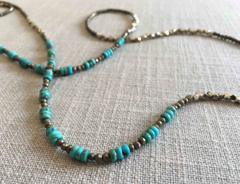 closeup of gemstone bead necklace comprising turquoise, silver and dark grey pyrite