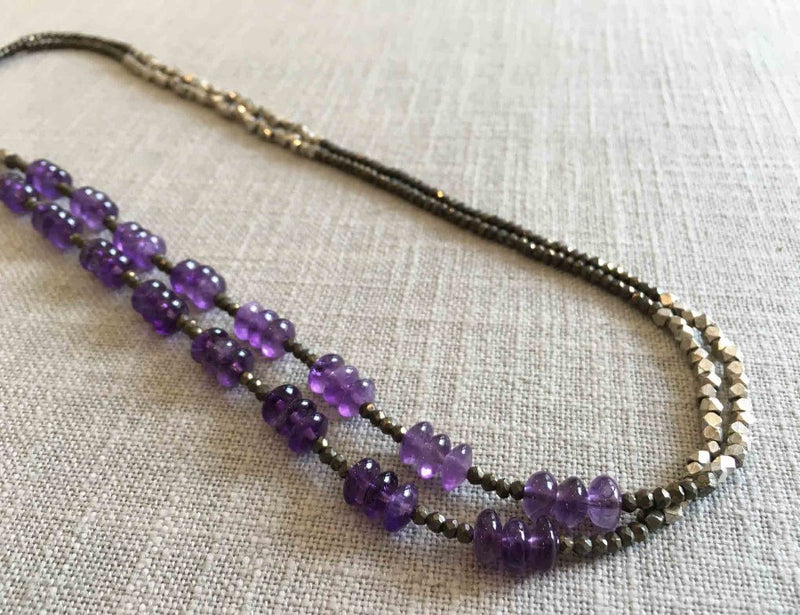 top view of gemstone bead necklace comprising purple amethyst, silver and dark grey pyrite